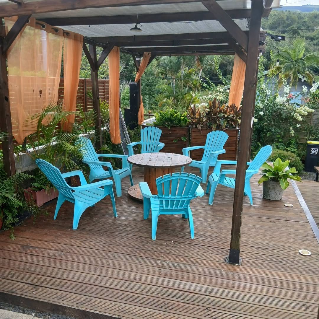 Terrasse couverte avec table ronde et fauteuils turquoise face au jardin